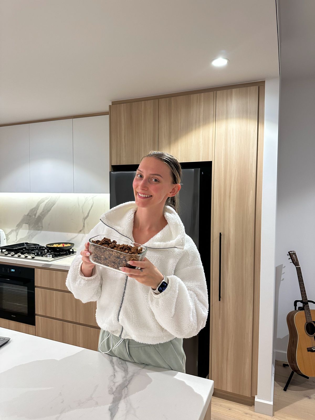 Danica in her kitchen, holding a container of granola